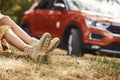 Particle view of girl that lying down on the ground in forest against modern car