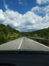 Road in the mountains seen from the windshield of the traveling car.