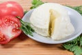 Partly cut soft cheese ball among the tomatoes and greens Royalty Free Stock Photo