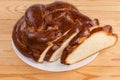 Partly sliced baked sweet braided bread on a white dish