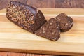 Partly sliced brown bread triangular shape on cutting board closeup Royalty Free Stock Photo