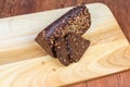 Partly sliced brown bread triangular shape on cutting board closeup Royalty Free Stock Photo