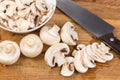 Partly sliced button mushrooms and kitchen knife on cutting board Royalty Free Stock Photo