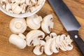 Partly sliced button mushrooms and kitchen knife on cutting board Royalty Free Stock Photo
