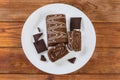 Partly sliced chocolate roll, dark chocolate on dish, top view