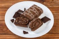 Partly sliced chocolate roll and dark chocolate pieces on dish