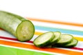 Partly sliced organic cucumber on a stripy colorful ceramic plate