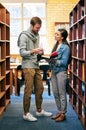 Partnering up to get their latest assignment done. two university students working together in the library at campus. Royalty Free Stock Photo