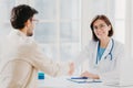 Partnership, assistance, trust and medicine concept. Female doctor shakes hands with thankful patient for good treatment and Royalty Free Stock Photo