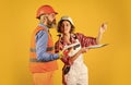 partnership. Builder Couple Look At Home Plans. couple looking at a blueprint. woman and man wear safety hardhat. family