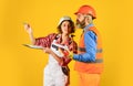 Partnership. Builder Couple Look At Home Plans. couple looking at a blueprint. woman and man wear safety hardhat. family