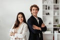 Partnership concept. Successful european man and latin woman standing with arms crossed and smiling, office interior Royalty Free Stock Photo