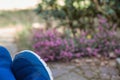 Parts of blue slippers in raised feet in front of an intentionally blurred garden with flowers, concept picture for rest,