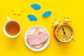 Parts of day. Morning. Time for breakfast. Tea, sandwich near alarm clock, sun and clouds cutout on yellow background Royalty Free Stock Photo