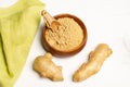 Parts of a ginger powder in a wooden bowl and a ginger root on a white background Royalty Free Stock Photo