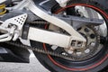 Parts of a motorcycle focusing on the rear wheel and motor chain link Royalty Free Stock Photo