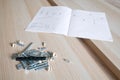 Parts of unfinished furniture , metal screws and tools lying on the floor with instruction manual for furniture assembly Royalty Free Stock Photo