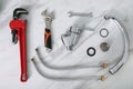 Parts of water tap and wrenches on white marble countertop, flat lay