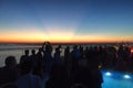 Party crowd of people having fun at roof top club with pool at sunset