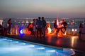 Party crowd of people having fun at roof top club with pool at sunset