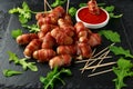 Party finger food pigs in blankets on toothpicks with ketchup sauce and wild rocket leaves Royalty Free Stock Photo