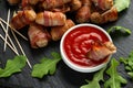 Party finger food pigs in blankets on toothpicks with ketchup sauce and wild rocket leaves Royalty Free Stock Photo