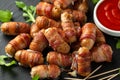 Party finger food pigs in blankets on toothpicks with ketchup sauce and wild rocket leaves Royalty Free Stock Photo