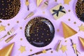 Party flat lay with black and golden plates, forks, gift, champagne bottle and star confetti