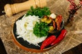 Bar snacks portion on wooden board: cecil cheese, hot peppers, olives, sun-dried tomatoes, fresh parsley leaves.