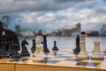 Party game white and black chess pieces on a wooden board against the backdrop of a city and sky with clouds Royalty Free Stock Photo