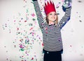 Party girl in colorful spotlights and confetti smiling on white background celebrating brightful event, wears stripped Royalty Free Stock Photo