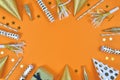 Party objects like paper hats, confetti, golden champagne bottles and star confetti forming frame around orange background Royalty Free Stock Photo