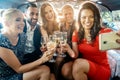Party people in a limo with drinks taking a selfie with phone Royalty Free Stock Photo
