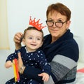 Party, Purim. Senior woman having fun with grandson, holding funny crown on a stick