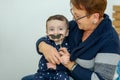 Party, Purim. Senior woman having fun with grandson, holding funny mustache on a stick