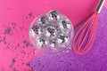 Party rave, greeting card concept. Pink kitchen whisk shaked decorative shining disco balls into small silver stars on Royalty Free Stock Photo