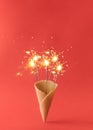 Party sparklers in an ice cream cone on a red background. Minimal new Year\'s concept Royalty Free Stock Photo