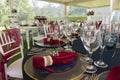 Party table in a garden, decorated with red napkins and glass cups with a background of white chairs Royalty Free Stock Photo