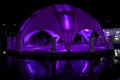 Party tent or pavilion at night on a lake with purple lights