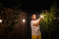 Party time in backyard with happy man hanging string lights in trees