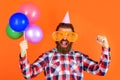 Party time. Joy, fun and happiness concept. Happy Man with balloons. Bearded man in party cap and big glasses. Royalty Free Stock Photo