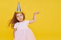 Party time. A joyful cute little child girl in a festive cap and elegant dress celebrates her birthday Royalty Free Stock Photo