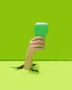 A party toast minimal macho concept. Man hand holding pint of green alcohol pops out from pastel green floor