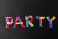 Party word made of multicolored papers on black