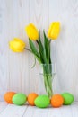 Paschal card, easter eggs and bouquet of spring flowers, decoration design. Light wooden background. Holiday, festive still life Royalty Free Stock Photo