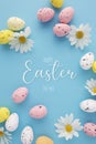 Paschal eggs with daisy flowers and Happy Easter to you lettering on blue background Royalty Free Stock Photo