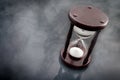 The passage of time and the ephemerality of life concept with hourglass surrounded by smoke or gof on a dark background with copy