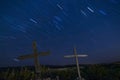 Two old crosses in an ancient cemetary against a blue twilight sky with star trails