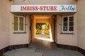 Passageway of a residential building with barred windows and an advertisement for a snack bar in Vienna Favoriten