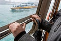 Passanger holding rail on taxi boat and looking through a window.
